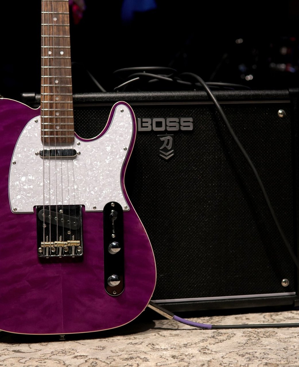 A purple electric guitar leaning against a combo amp