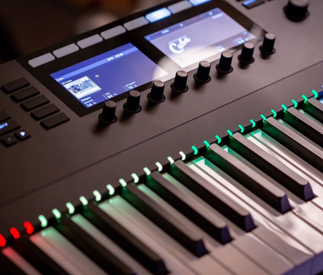 Close-up of a lit synthesizer keyboard with knobs and screens
