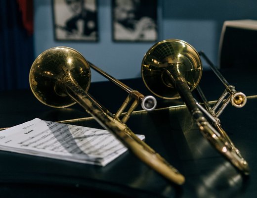 Two brass trombones resting on stands