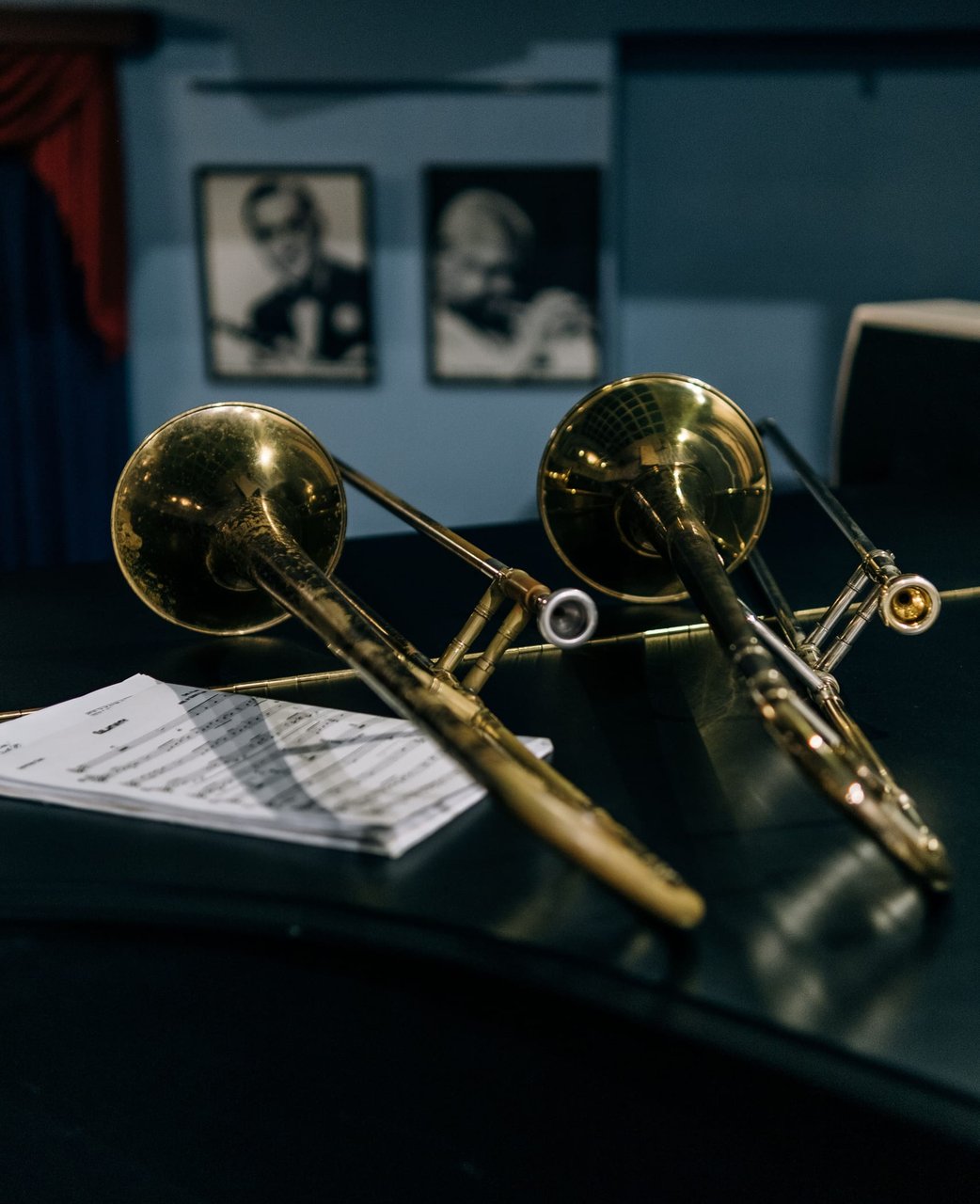 Two brass trombones resting on stands
