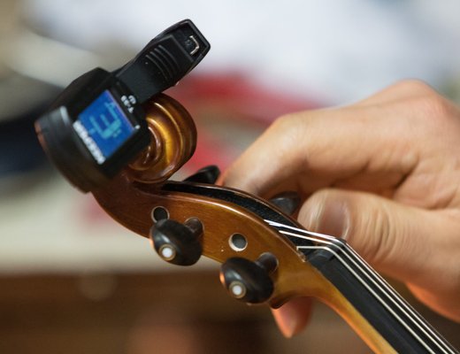 Hands turning the tuning pegs on a violin scroll